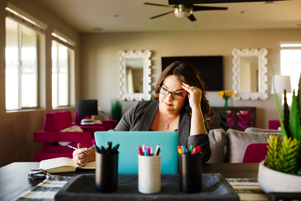 Teacher holding her head working on laptop