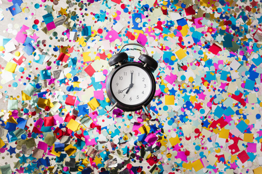 Old fashioned clock in the middle of confetti  showing 7 pm, the time the Writing Masterclass registration closes on July 1st