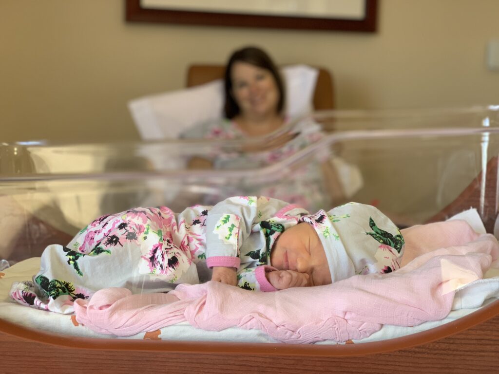 Baby Adalynn, conceived with infertility treatments, sleeping in bassinet in flowered outfit and hat