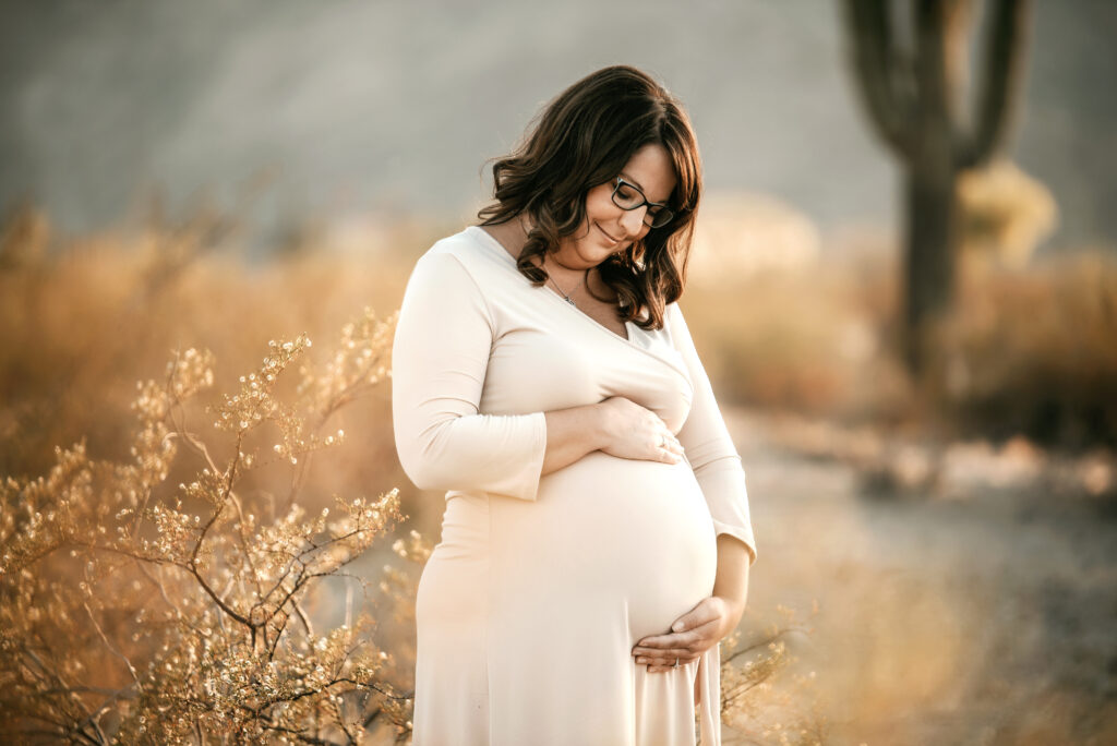 Woman in white dress holding belly during pregnancy after infertility