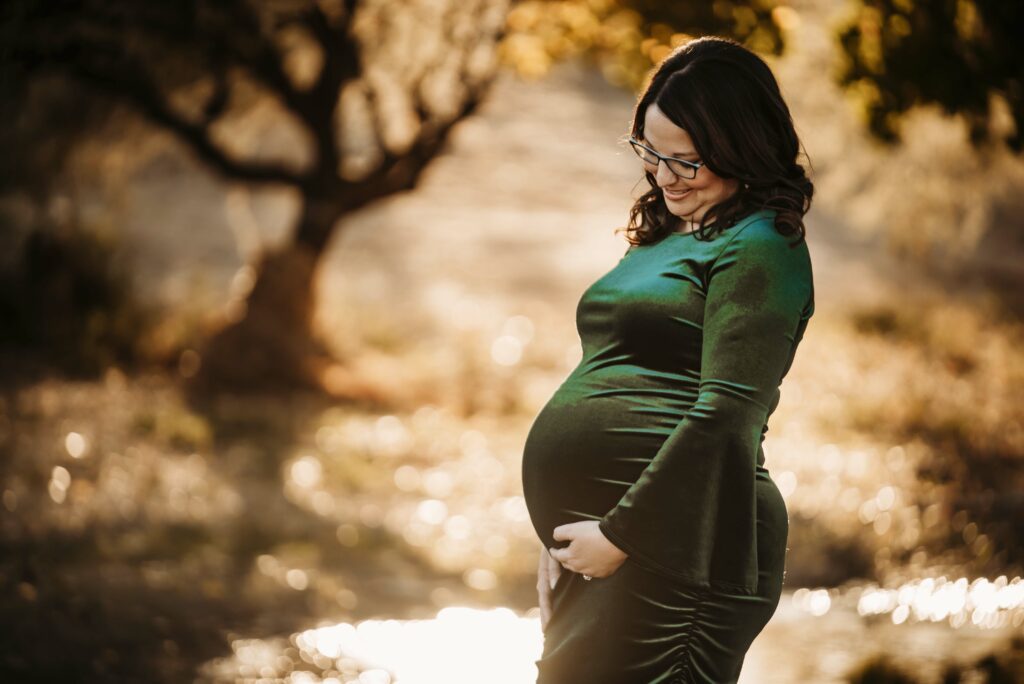 Jamie in green dress holding belly after infertility procedures resulted in pregnancy with Violet