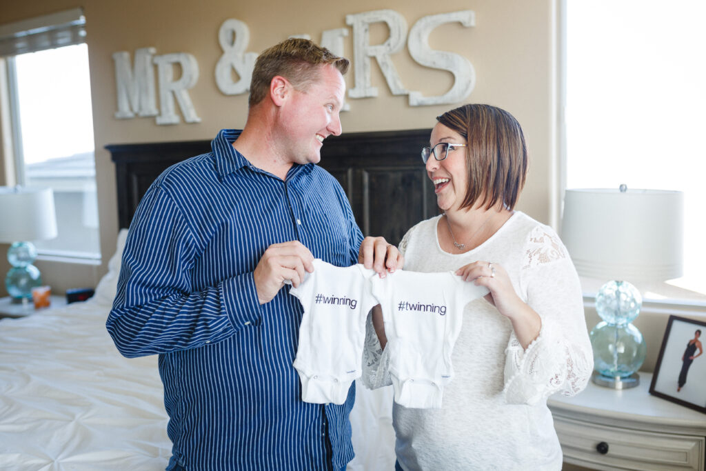 Couple holding up "twinning" onesies