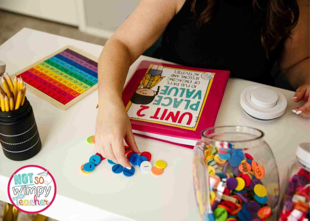 image shows teacher's hand with math curriculum binder and manipulatives